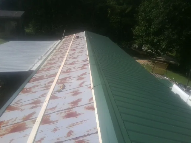 Old rusted panels beside newly installed green metal roofing — Wind Damage Roof Repair by Roofing Brothers in Clovis