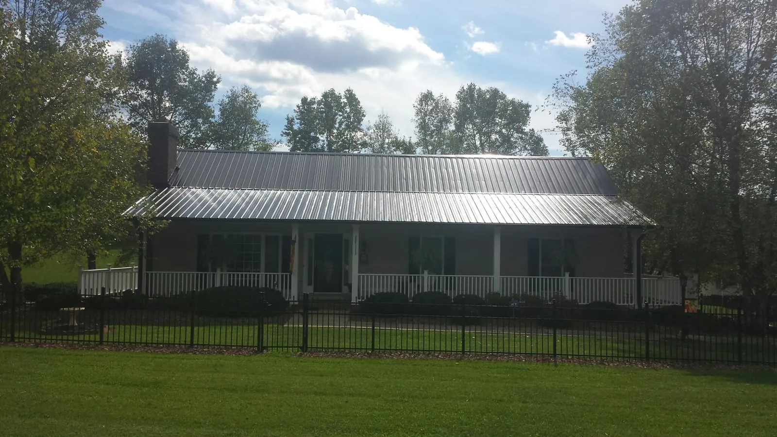 Gray metal roof on a brick ranch with a full width front porch — Gutter Guard Installation work by our crew in Clovis