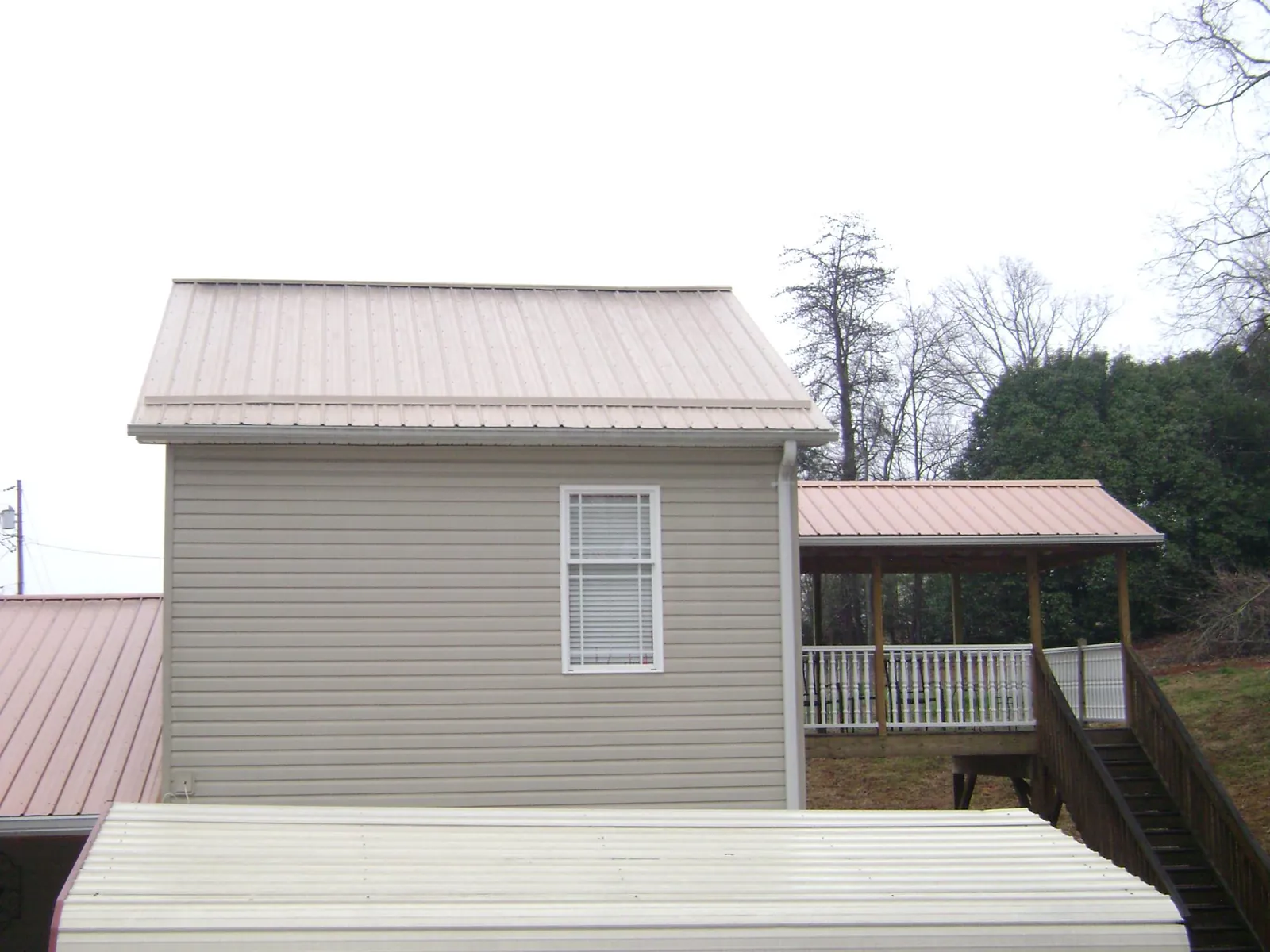 Tan metal roofs on a two story addition and attached porch, from a Roof Replacement job in Clovis